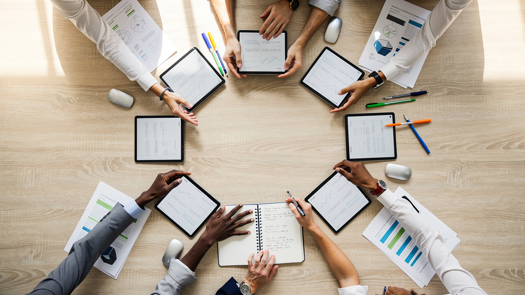 Team members collaborating around digital devices and tools