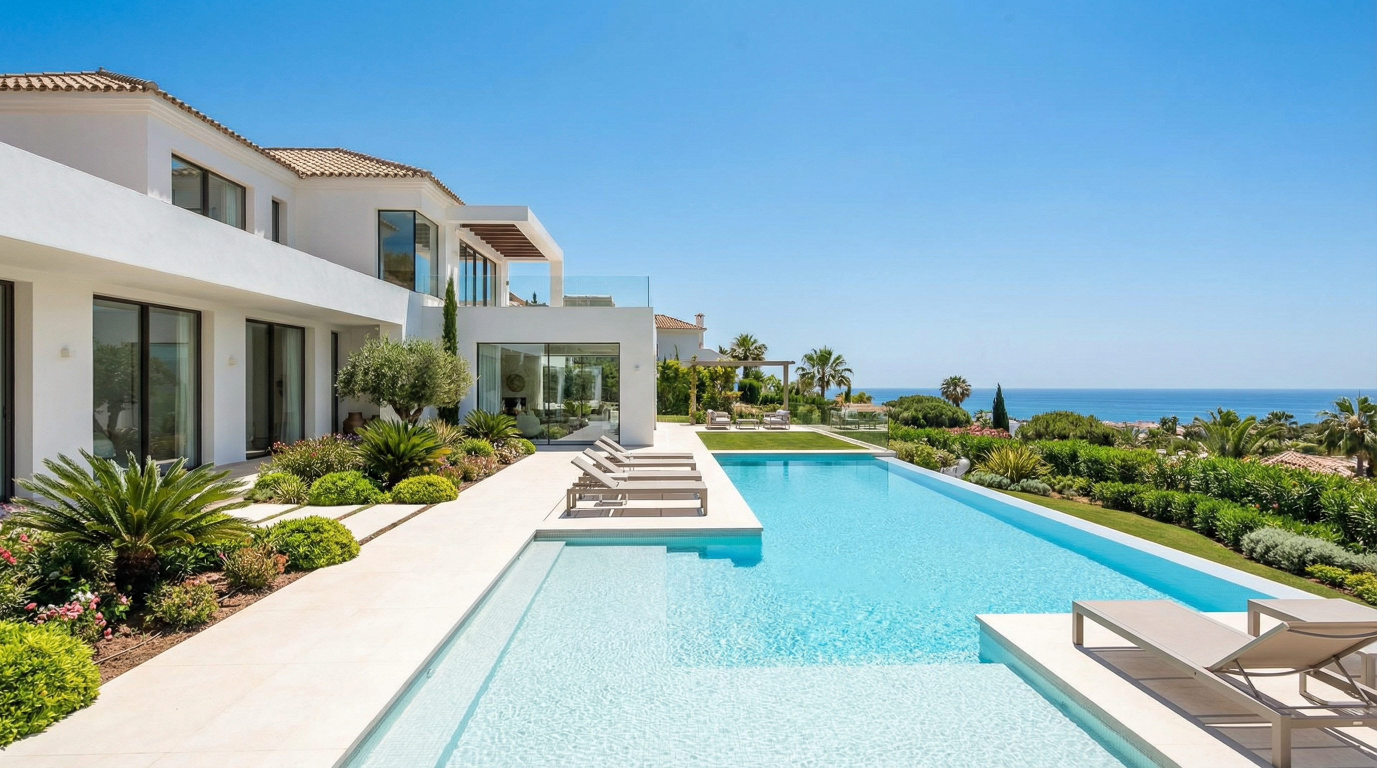 En modern medelhavsvilla i Costa del Sol som visar elegant arkitektur, lummiga trädgårdar och en lugn utomhusterrass under en livlig blå himmel.