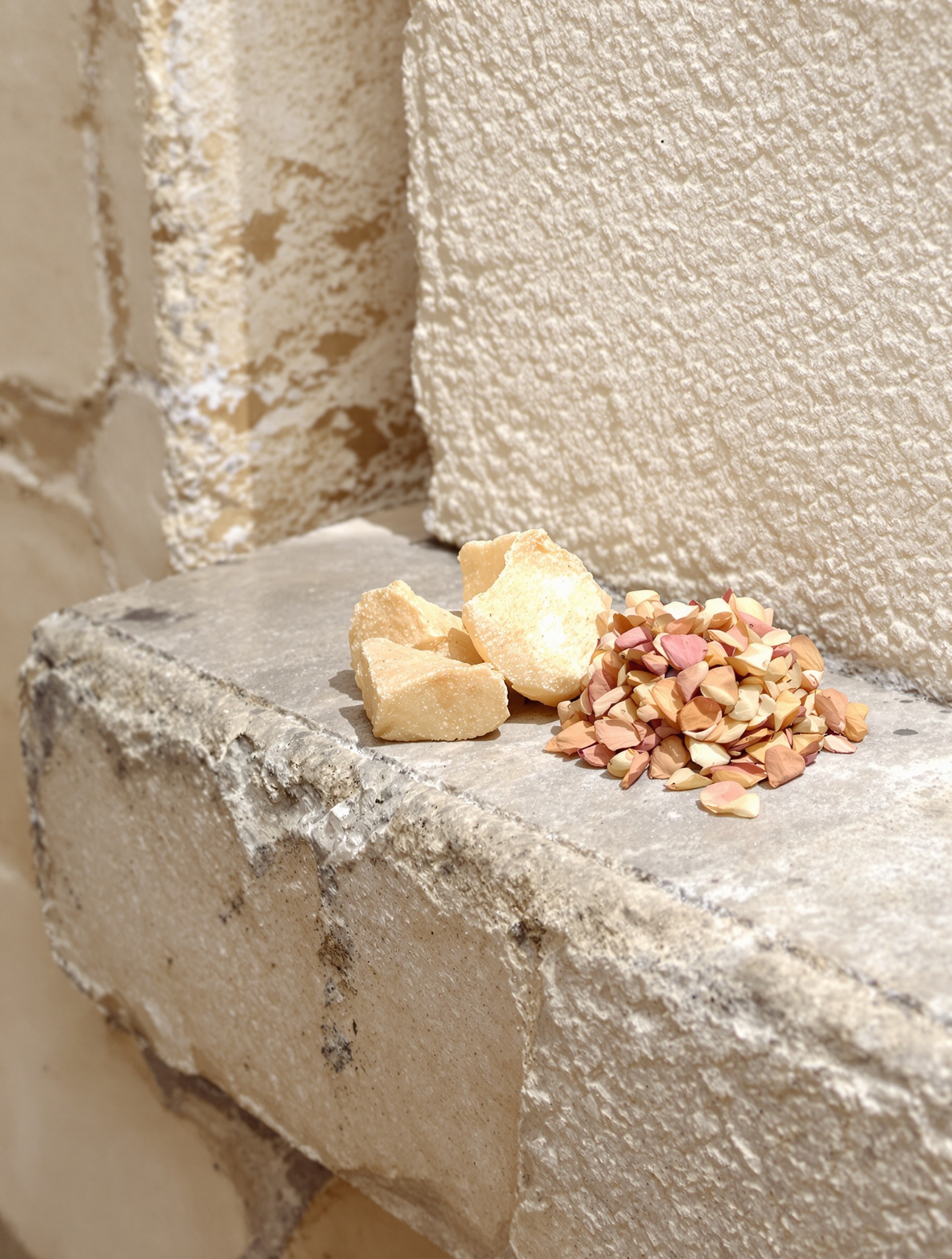 Raw frankincense resin tears and browning rose petals resting on an ancient stone ledge for Guidance 46 by Amouage.