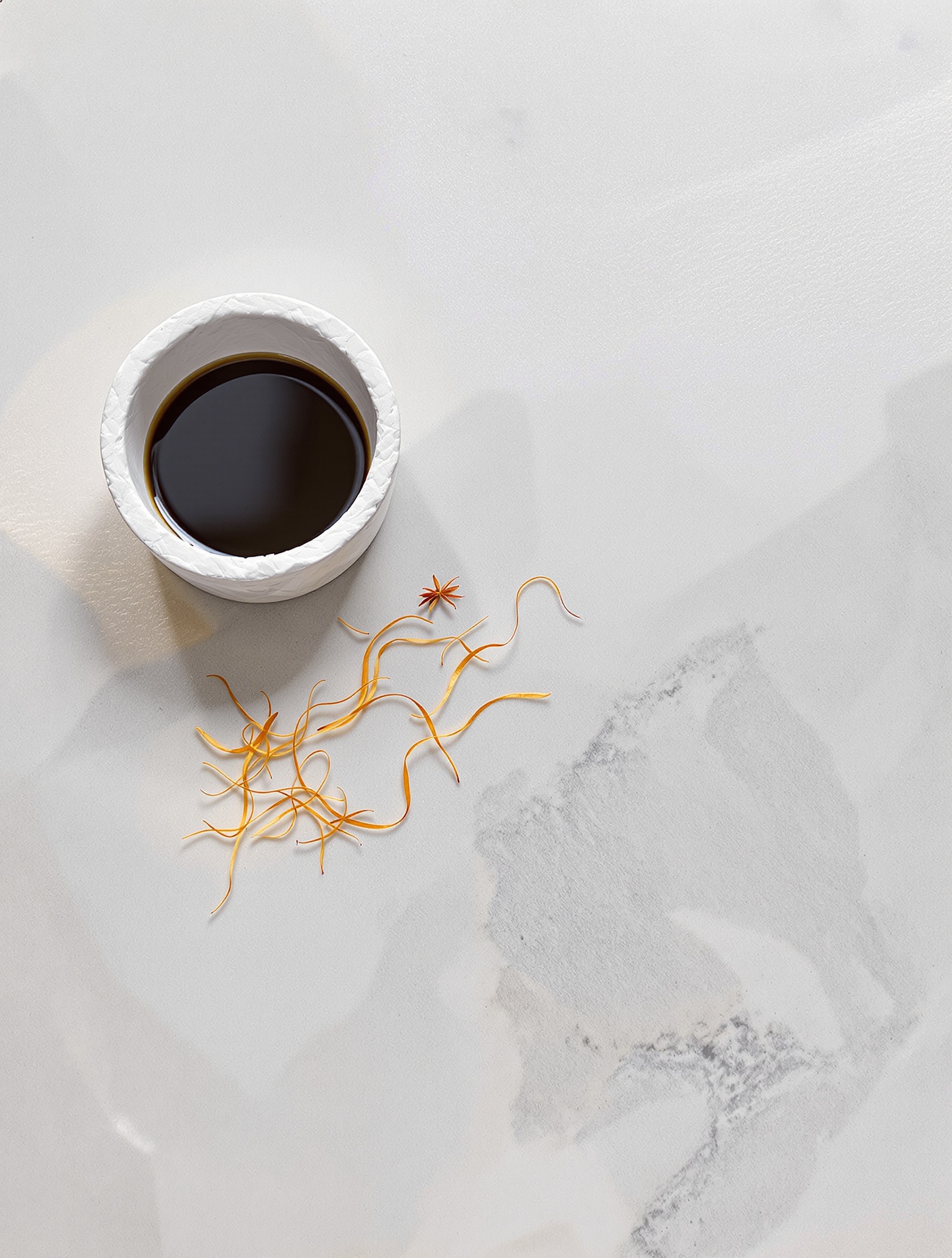 Saffron threads on pale mineral stone beside a dark water pool evoking the cold spice tension of Ganymede.