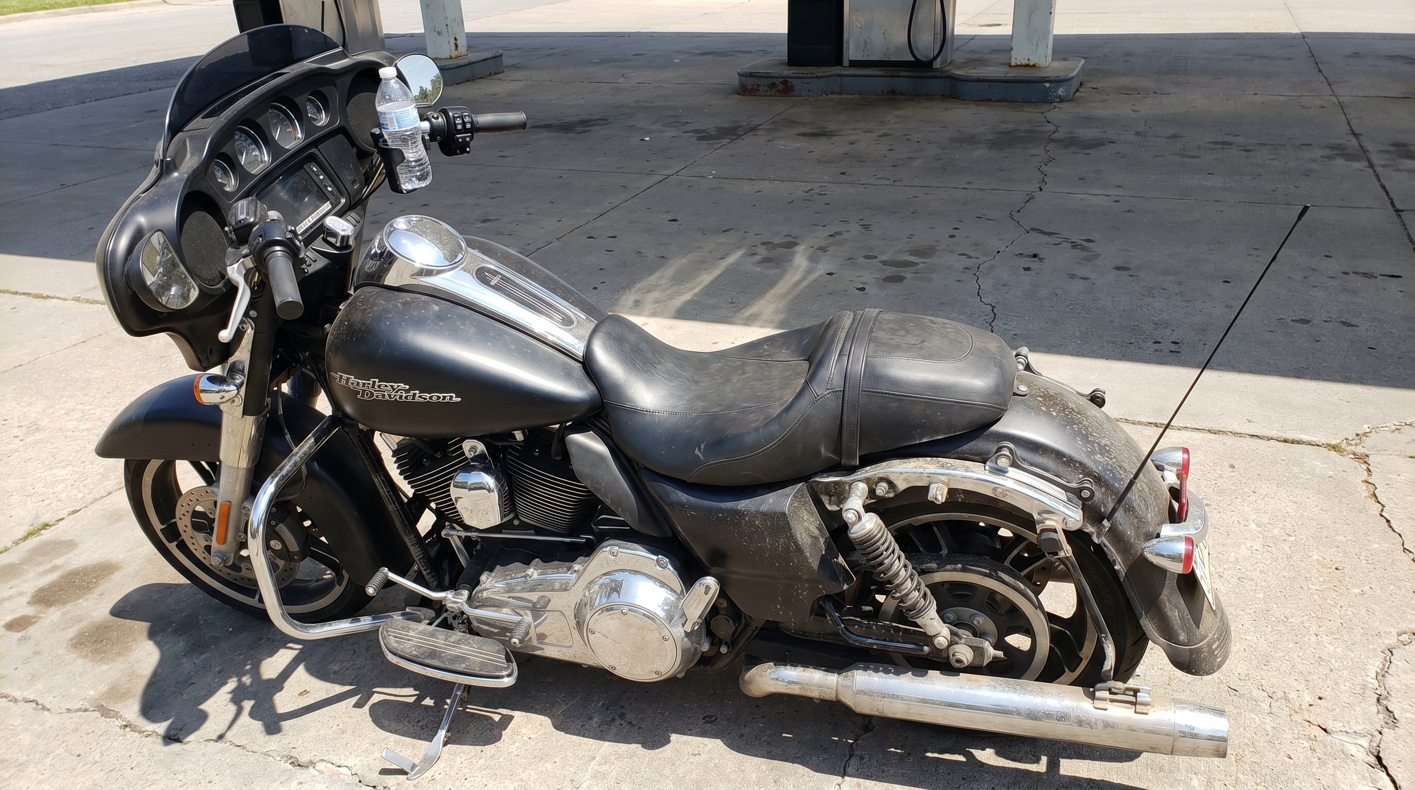 Close view of a Harley Street Glide stock seat baking in direct summer sun at a gas station parking lot