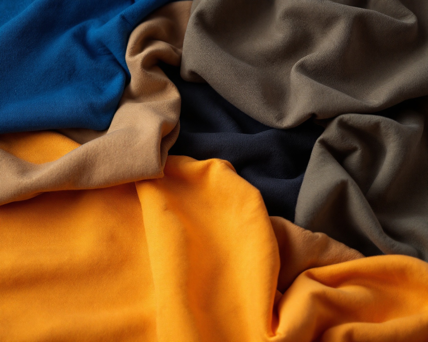 Abstract close-up of folded heavyweight cotton tees in earth tones, emphasising texture and weight, soft natural light, no people or text