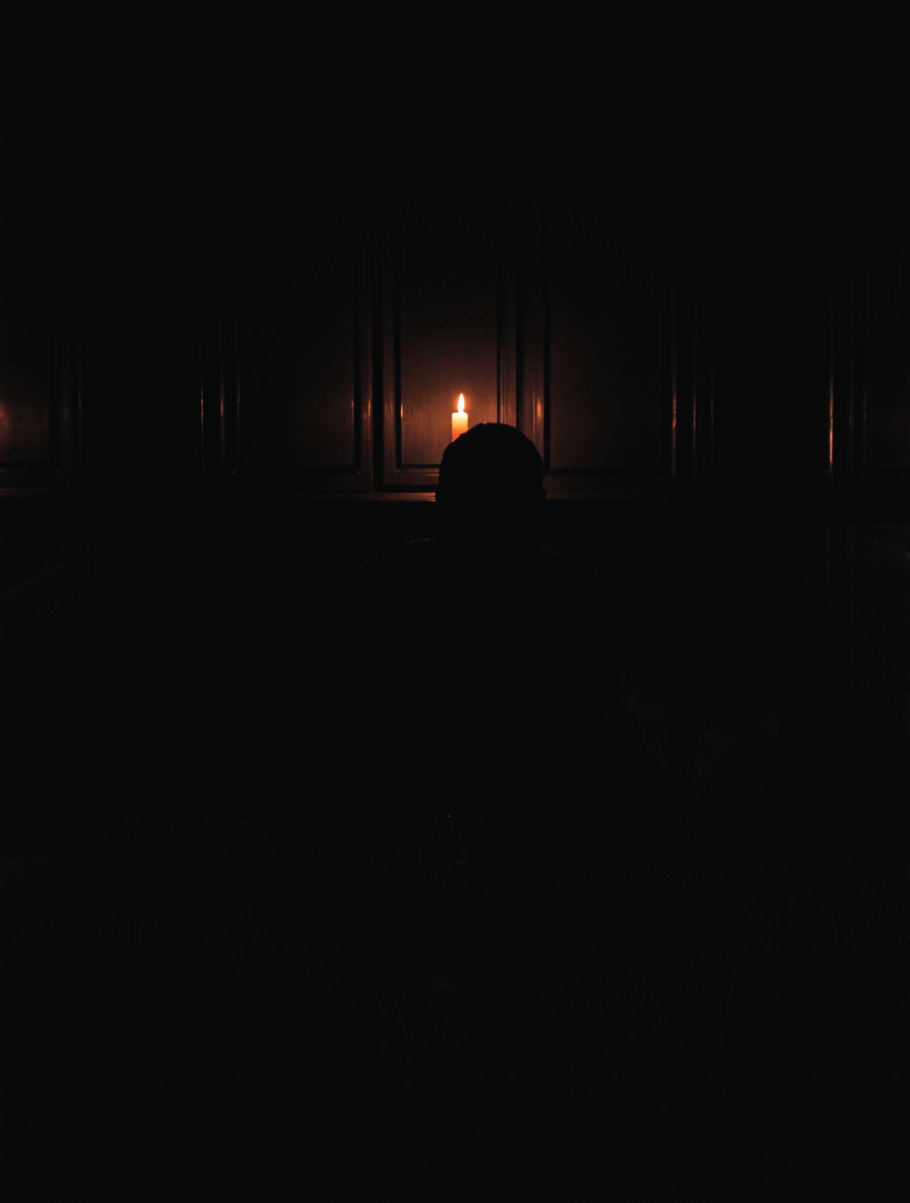 A silhouetted figure seated alone at a dark wooden table holds a whiskey glass in guttering candlelight, their face turned away into shadow.