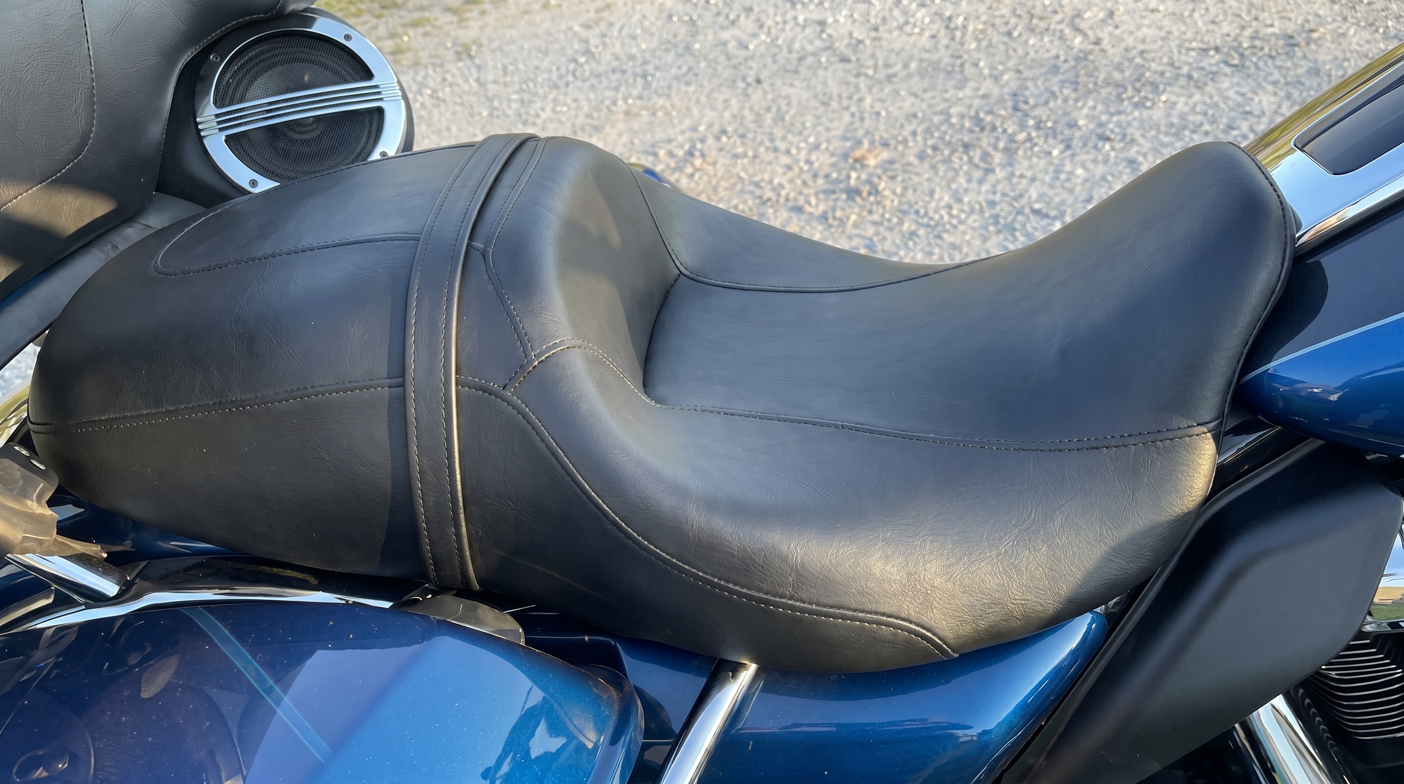 Close angle of Harley Street Glide stock black vinyl seat showing smooth solid surface that traps body heat and pressure