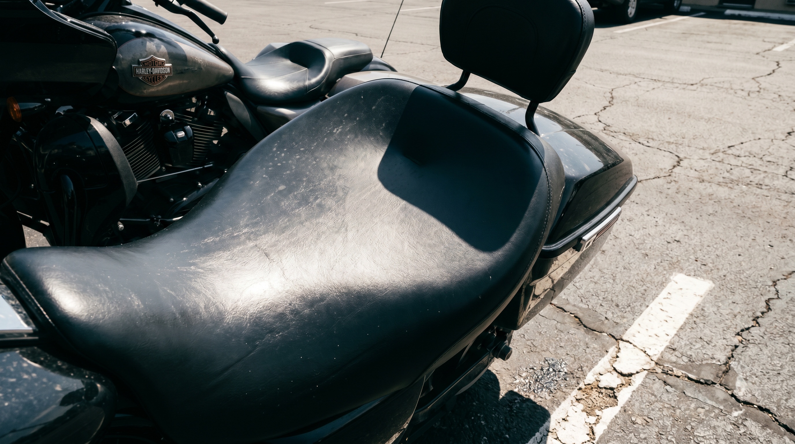 Close view of hot black factory vinyl Harley seat in direct sunlight showing heat-trapping surface