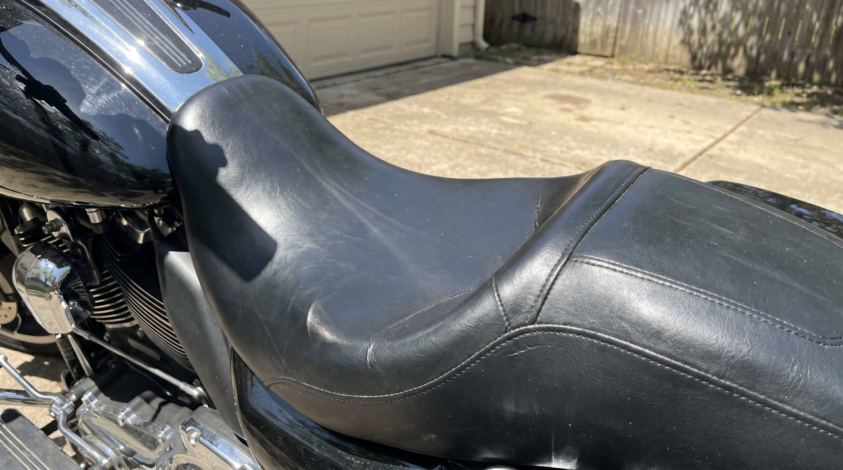 Close view of stock black vinyl Harley seat under hot sun showing heat-trapping smooth surface