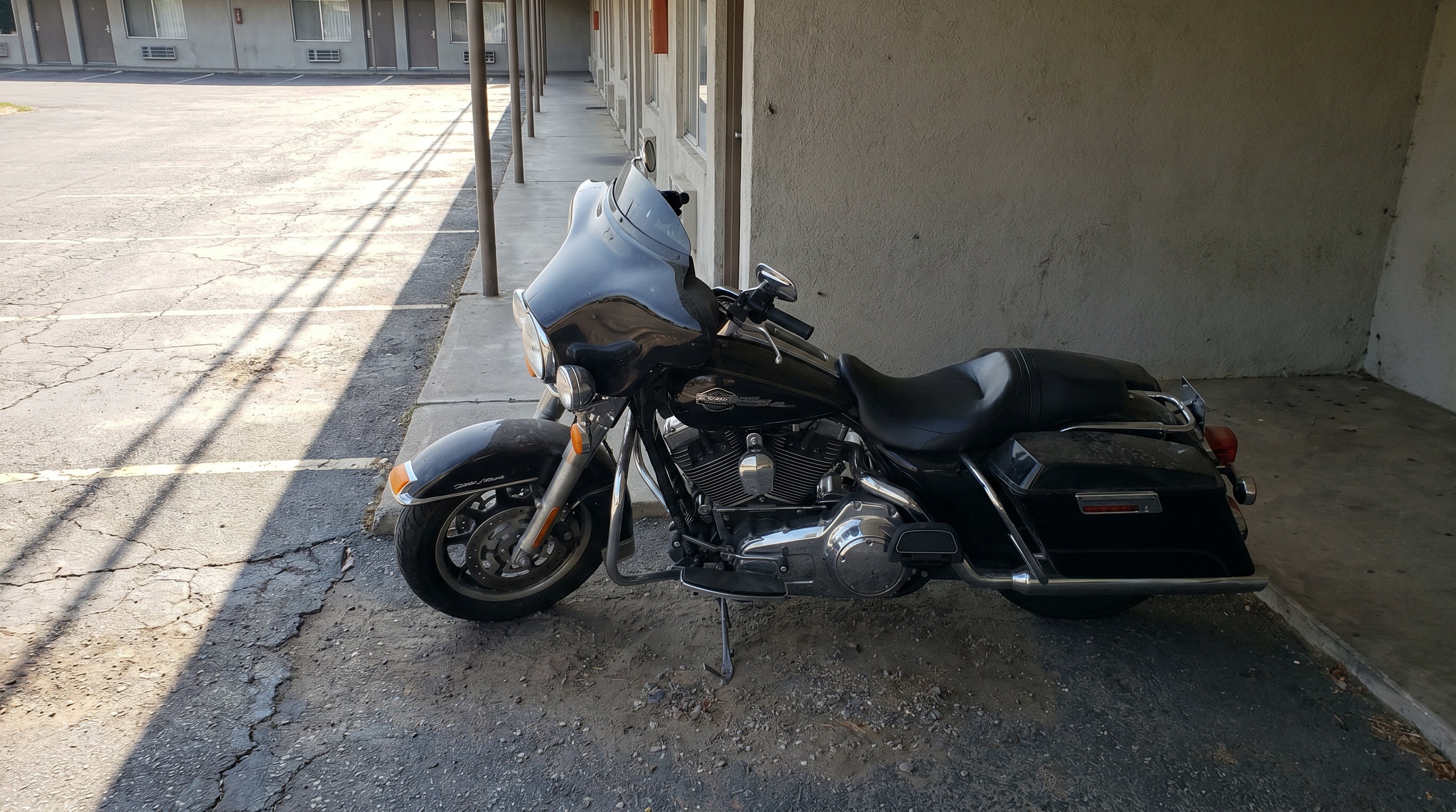 Harley bagger parked in cool shade of a building to keep the motorcycle seat shaded