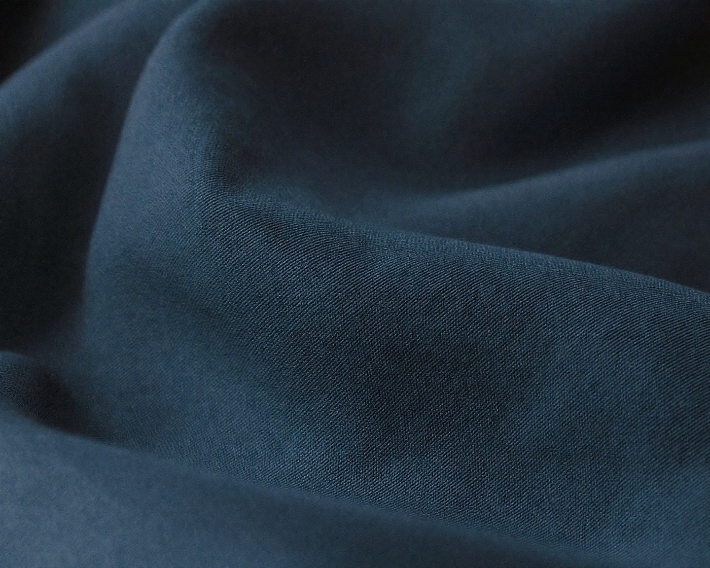 Close-up of fabric texture with soft focus, natural cotton weave visible, muted tones, editorial product photography style