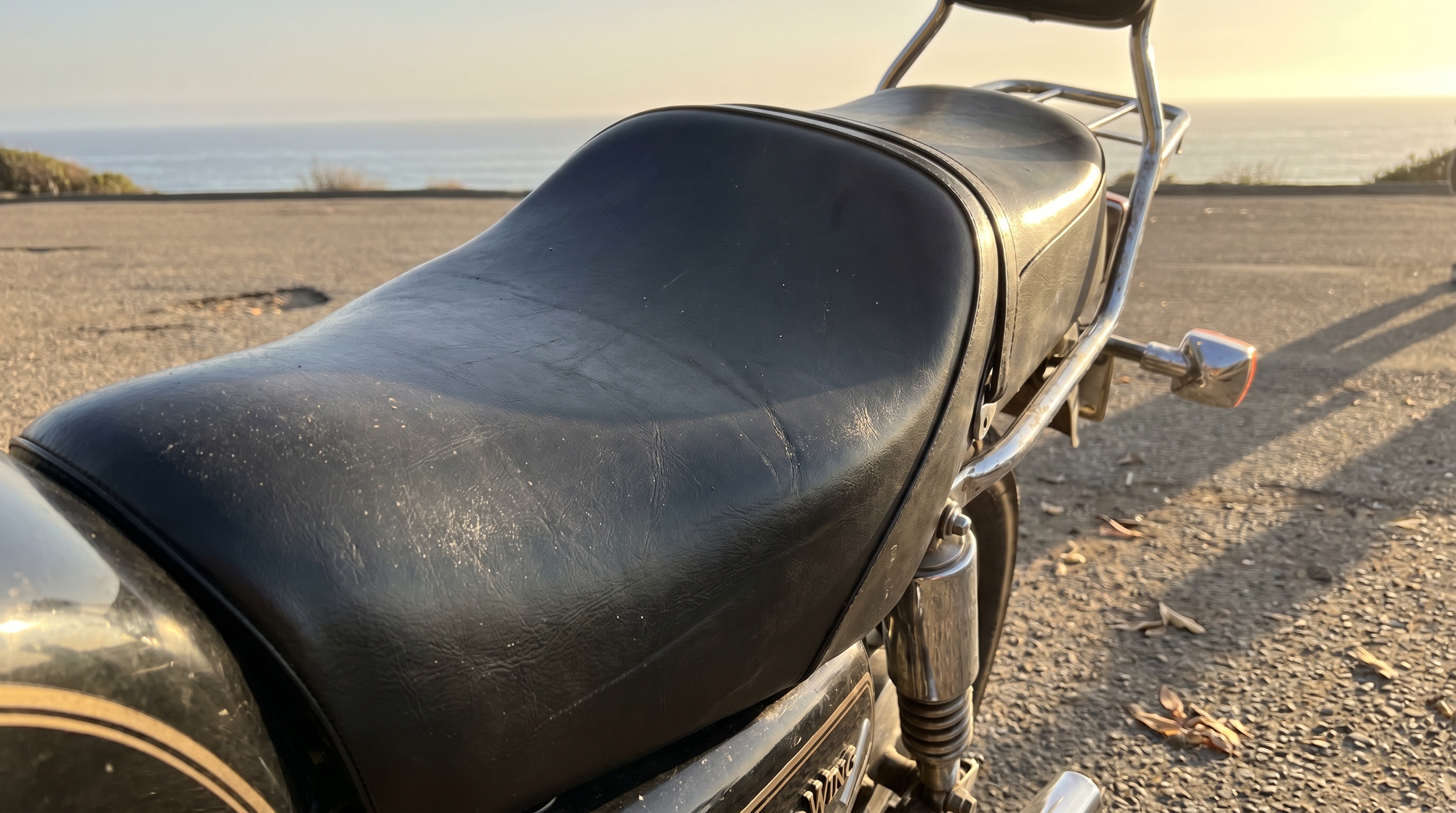 Close side profile of Honda Gold Wing stock black vinyl seat baking in late afternoon sun showing heat buildup