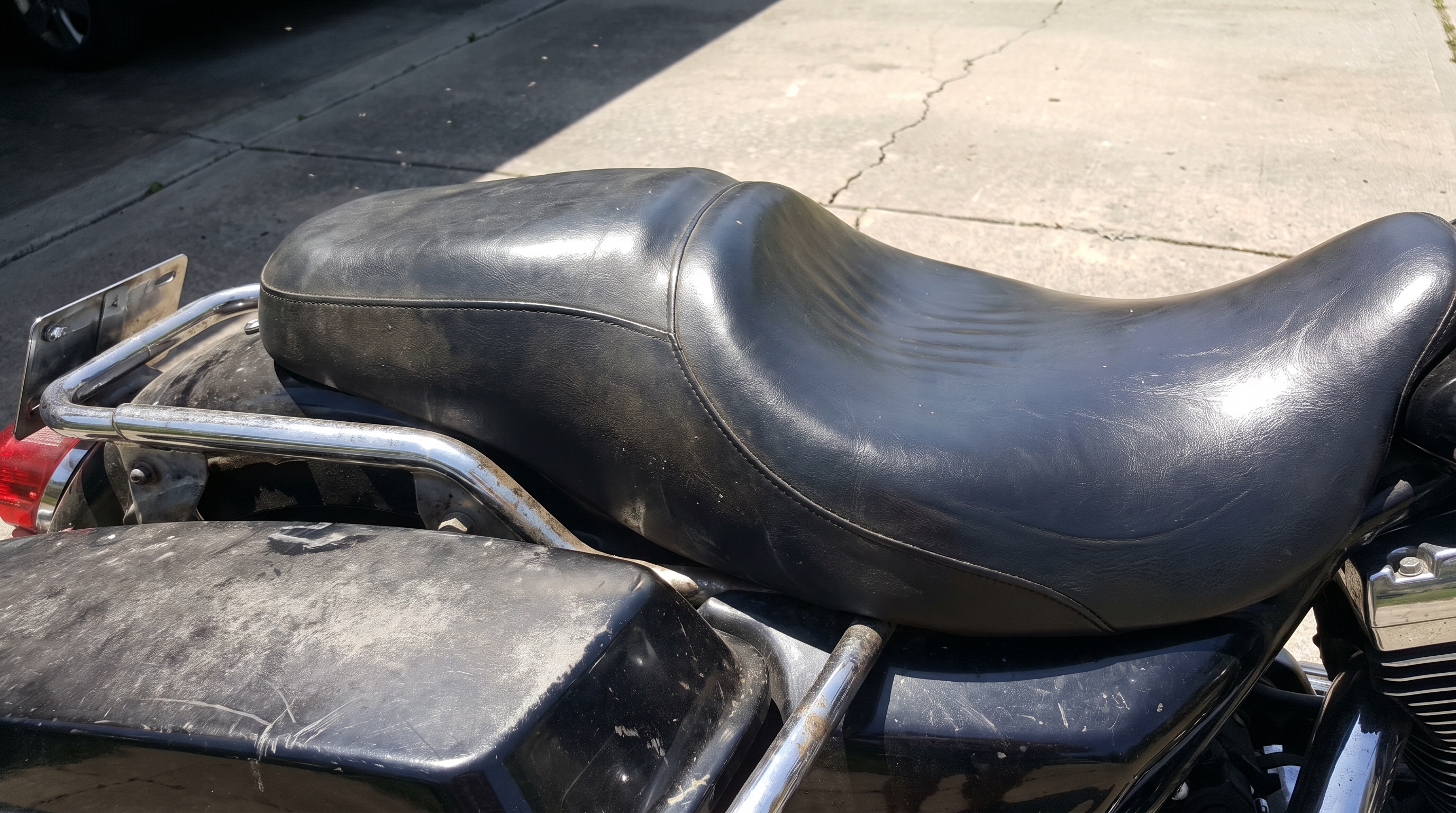 Close side view of a Harley Ultra stock vinyl seat baking in sun, showing why factory seats trap heat