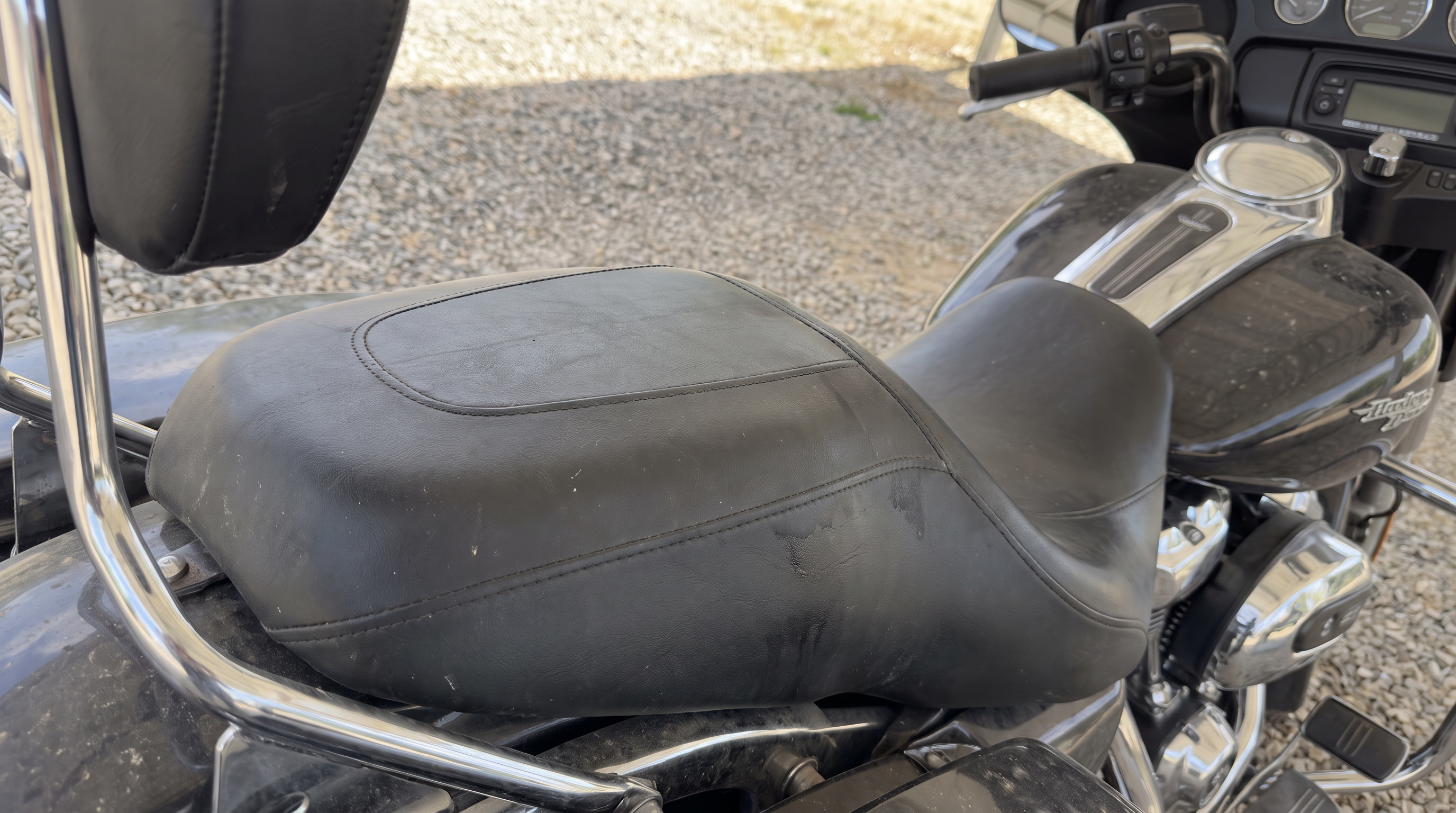 Close view of a Street Glide stock black vinyl seat and lower backrest showing heat buildup on smooth factory vinyl
