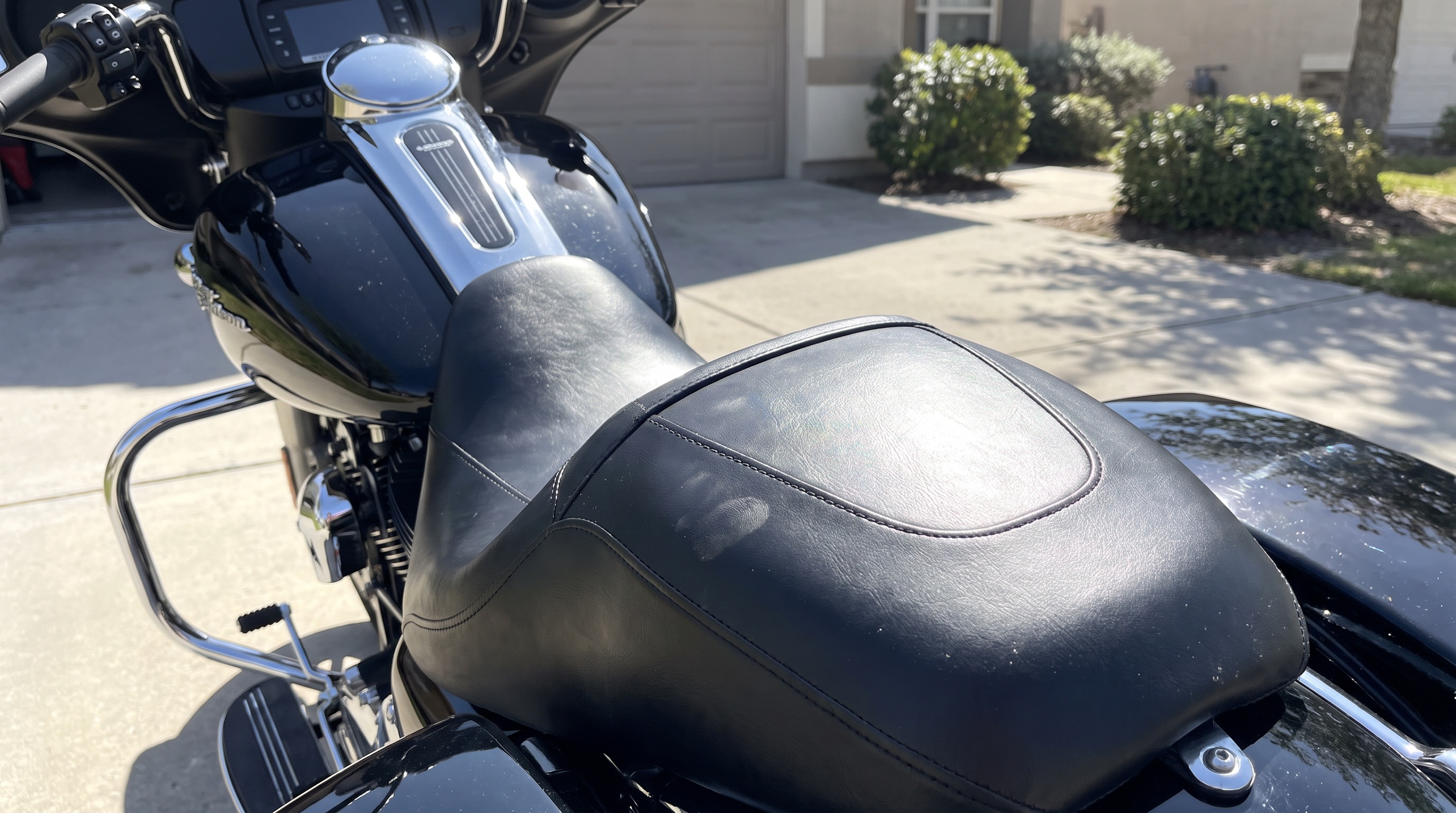 Bare factory black vinyl Harley seat baking in afternoon sun, showing why stock seats trap heat