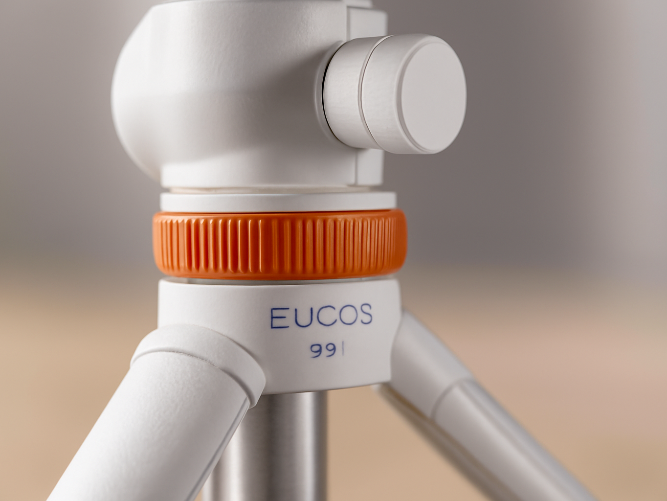 Macro close-up of white EUCOS tripod leg joint with twist-lock detail and aluminum texture