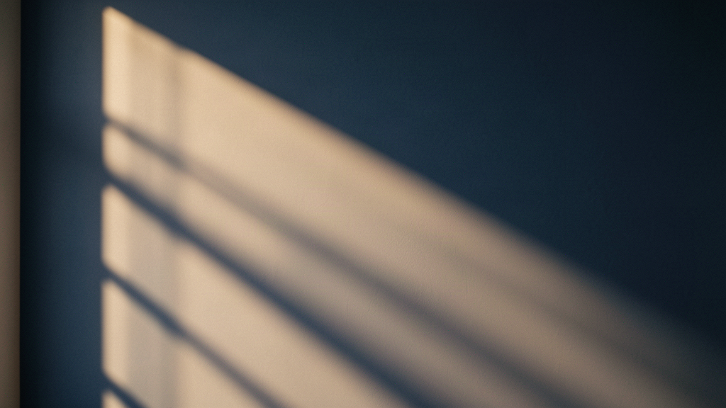 Morning light falling through clinic window blinds on a quiet navy wall