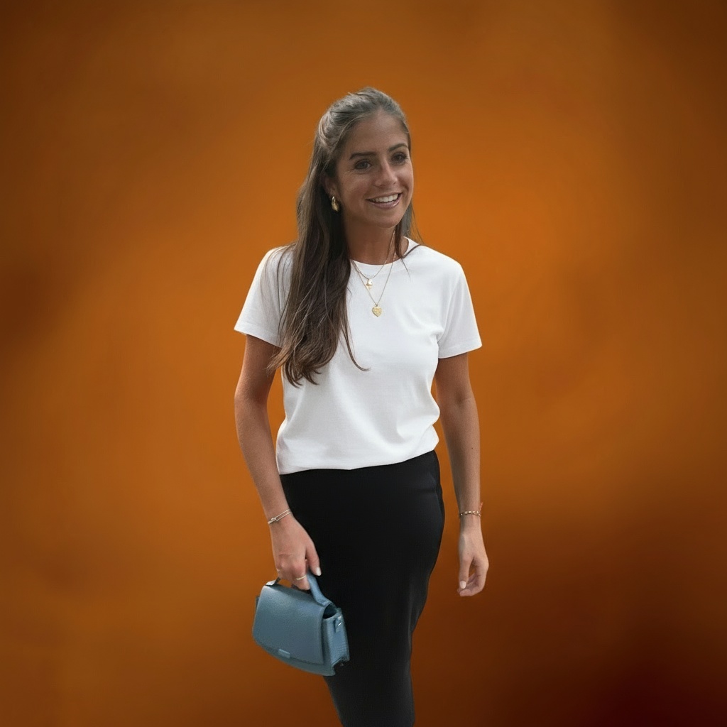 A smiling Carolyn October wearing stylish attire, slightly turned to the right, in a vibrant outdoor setting.